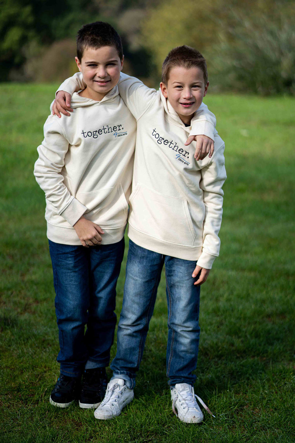 Zwei Jungen tragen im Partnerlook den 4littlearts Kinderhoodie in Creme mit 'together' Schriftzug als Stickerei auf der Brust.